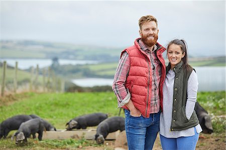 simsearch:614-06043441,k - Couple on pig farm looking at camera smiling Stock Photo - Premium Royalty-Free, Code: 649-08824781
