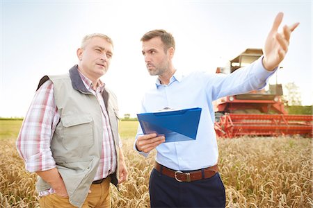 food production - Farmer and businessman in wheat field holding clipboard looking away Stock Photo - Premium Royalty-Free, Code: 649-08825144