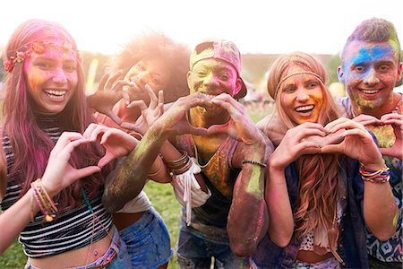 Portrait of group of friends at festival, covered in colourful powder paint, making heart shapes with hands Photographie de stock - Premium Libres de Droits, Code: 649-08825189