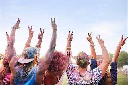 simsearch:649-08825183,k - Group of friends at festival, covered in colourful powder paint, arms raised, making peace sign with fingers, rear view Foto de stock - Sin royalties Premium, Código: 649-08825199