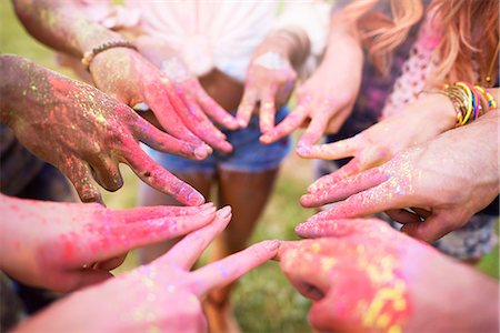 Group of friends at festival, covered in colourful powder paint, connecting fingers with peace signs, close-up Photographie de stock - Premium Libres de Droits, Code: 649-08825193