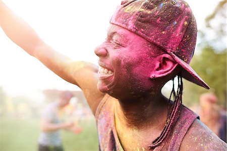 simsearch:649-08825183,k - Young man at festival, covered in colourful powder paint, arms raised, dancing Foto de stock - Sin royalties Premium, Código: 649-08825200