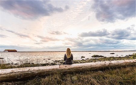 simsearch:649-09213591,k - Rear view of woman sitting on tree trunk looking out from  Wreck Beach at dusk, Vancouver, Canada Stockbilder - Premium RF Lizenzfrei, Bildnummer: 649-08825211