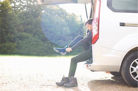 people in minivan - Man sitting in automobile boot putting on socks Stock Photo - Premium Royalty-Free, Code: 649-08825278