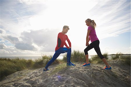 Couple on sand dune, hands on knee doing stretching exercises Foto de stock - Sin royalties Premium, Código: 649-08825299