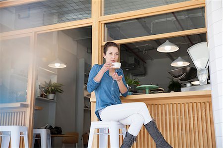 simsearch:649-08825304,k - Young woman sitting at bar in cafée, holding coffee cup Stock Photo - Premium Royalty-Free, Code: 649-08825306