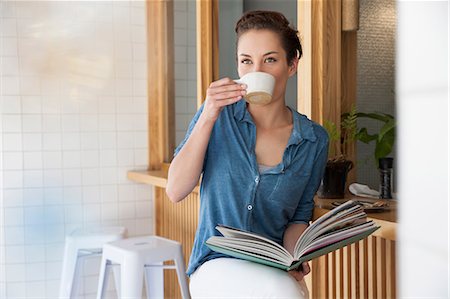 simsearch:649-08825304,k - Young woman sitting at bar in cafée, drinking coffee, holding book Stock Photo - Premium Royalty-Free, Code: 649-08825307