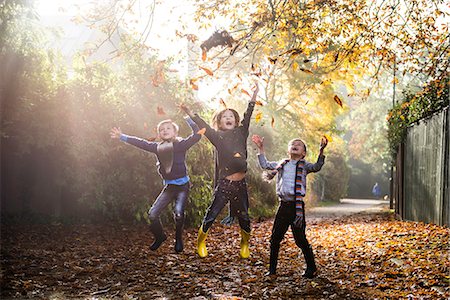sólo niños - Three young boys, playing outdoors, throwing autumn leaves Foto de stock - Sin royalties Premium, Código: 649-08839963