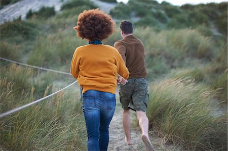 Couple running on grassy dune Photographie de stock - Premium Libres de Droits, Code: 649-08840015