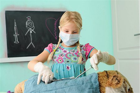 pathology - Girl pretending to be vet operating on toy tiger Stock Photo - Premium Royalty-Free, Code: 649-08840107