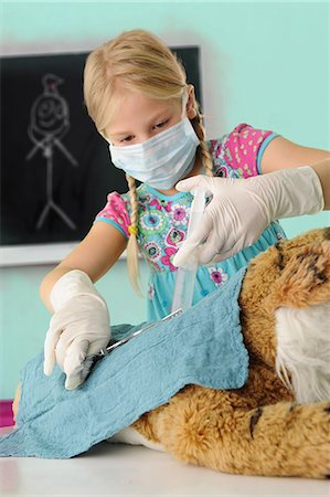 pathology - Girl pretending to be vet giving toy tiger syringe injection during operation Stock Photo - Premium Royalty-Free, Code: 649-08840108