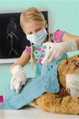 patología - Girl pretending to be vet giving toy tiger syringe injection during operation Foto de stock - Sin royalties Premium, Código: 649-08840108