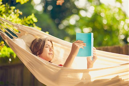 simsearch:614-08119697,k - Teenage boy relaxing in garden hammock reading a book Fotografie stock - Premium Royalty-Free, Codice: 649-08840140