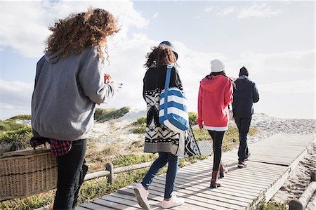 rear view of woman texting cellphone - Rear view of young adult friends strolling along beach boardwalk reading smartphones, Western Cape, South Africa Stock Photo - Premium Royalty-Free, Code: 649-08840219