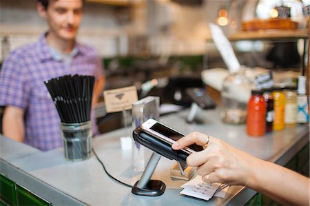 digital money - Cropped shot of female customer using smartphone contactless payment in  cafe Stock Photo - Premium Royalty-Free, Code: 649-08840252