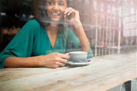 Mid adult woman chatting on smartphone in cafe window seat Foto de stock - Royalty Free Premium, Número: 649-08840294