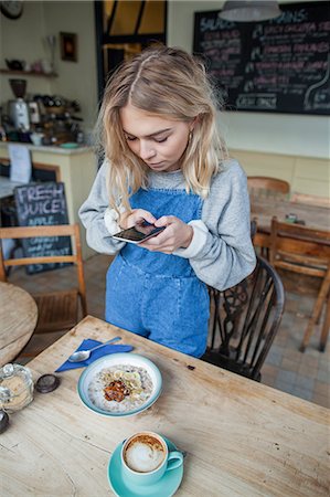 simsearch:649-08924663,k - Young woman in cafe, using smartphone Foto de stock - Royalty Free Premium, Número: 649-08840436