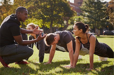 simsearch:614-07911952,k - Personal trainer instructing man and women doing push ups in park Fotografie stock - Premium Royalty-Free, Codice: 649-08840700