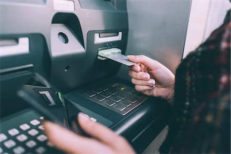Hand of young woman inserting credit card into cash machine Stock Photo - Premium Royalty-Free, Code: 649-08840728