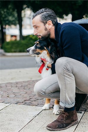 simsearch:649-08840788,k - Mid adult man crouching with pet dog on city sidewalk Foto de stock - Sin royalties Premium, Código: 649-08840786