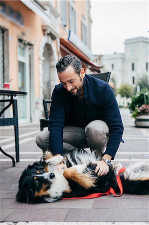 simsearch:649-08840788,k - Mid adult man crouching to pet dog in city square Foto de stock - Sin royalties Premium, Código: 649-08840797