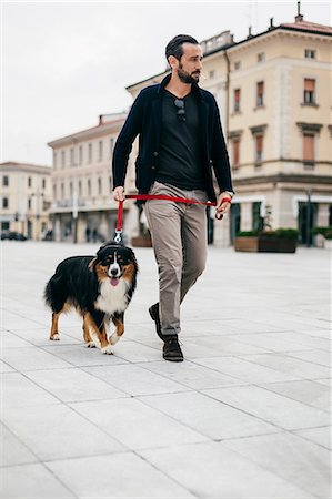 simsearch:649-08840788,k - Mid adult man walking dog at city square Foto de stock - Sin royalties Premium, Código: 649-08840790