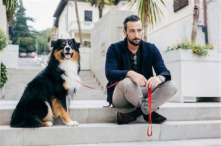 simsearch:649-08840788,k - Mid adult man sitting on stairway with pet dog in city square Foto de stock - Sin royalties Premium, Código: 649-08840791