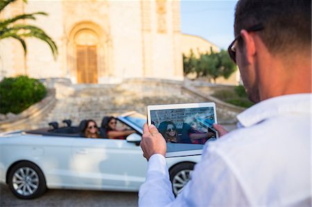 simsearch:614-06974581,k - Over shoulder view of man photographing two young women tourists in convertible, Calvia, Majorca, Spain Foto de stock - Sin royalties Premium, Código: 649-08840812