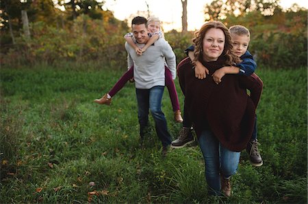 Parents giving children piggy back in field Stock Photo - Premium Royalty-Free, Code: 649-08859587