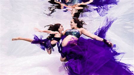 smiling women underwater - Pregnant woman and young child, draped in sheer fabric, face to face, underwater view Stock Photo - Premium Royalty-Free, Code: 649-08859721