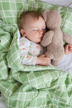 Overhead view of baby boy asleep on bed holding teddy bear Stock Photo - Premium Royalty-Free, Code: 649-08859767