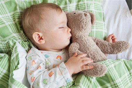 Overhead view of baby boy asleep on bed holding teddy bear Stock Photo - Premium Royalty-Free, Code: 649-08859768