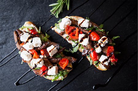 simsearch:649-08548244,k - Meat, feta and tomato open sandwiches with sauce garnish on slate Stock Photo - Premium Royalty-Free, Code: 649-08859787