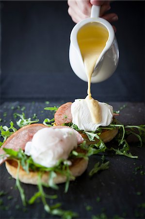 Female hand pouring hollandaise sauce over eggs benedict breakfast on slate Stock Photo - Premium Royalty-Free, Code: 649-08859789