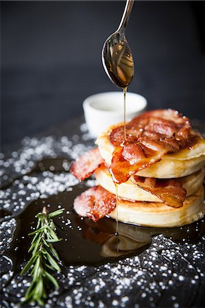 Breakfast bacon crumpet with maple syrup pouring from spoon onto slate Stock Photo - Premium Royalty-Free, Code: 649-08859796