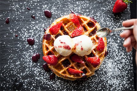 simsearch:649-08859795,k - Female hand holding spoon over strawberries and ice cream waffle on slate Foto de stock - Royalty Free Premium, Número: 649-08859799