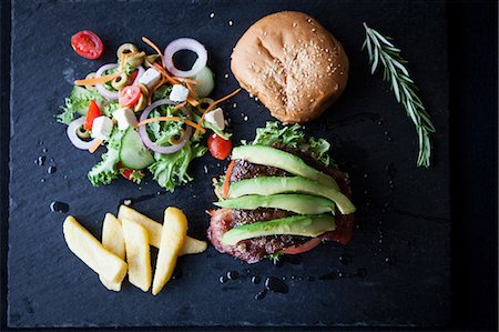 simsearch:649-08859791,k - Overhead view of hamburger with avocado, side salad and chips on slate Photographie de stock - Premium Libres de Droits, Code: 649-08859793