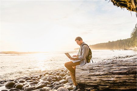 solo travel - Man sitting using laptop on beach in Juan de Fuca Provincial Park, Vancouver Island, British Columbia, Canada Stock Photo - Premium Royalty-Free, Code: 649-08859996