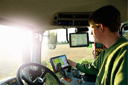 Young man driving tractor using touchscreen on global positioning system Fotografie stock - Premium Royalty-Free, Codice: 649-08860046