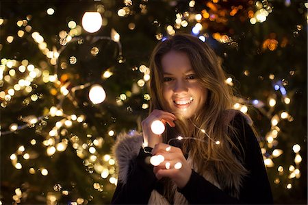 Young woman with lights in her hand, tree in background Stock Photo - Premium Royalty-Free, Code: 649-08860127