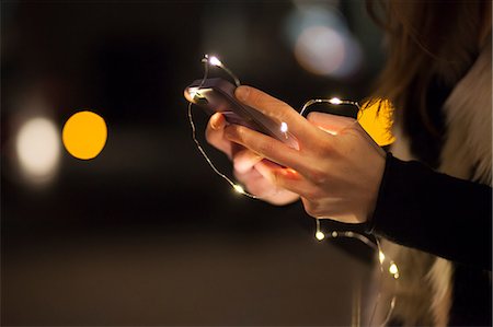 simsearch:694-03693899,k - Young woman holding mobile phone and lights, close up of hand Fotografie stock - Premium Royalty-Free, Codice: 649-08860129