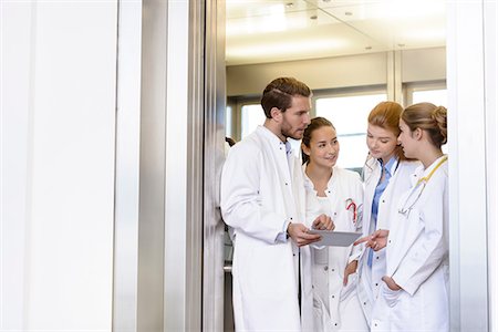 Male and female doctors using digital pad and talking in hospital Stock Photo - Premium Royalty-Free, Code: 649-08860186