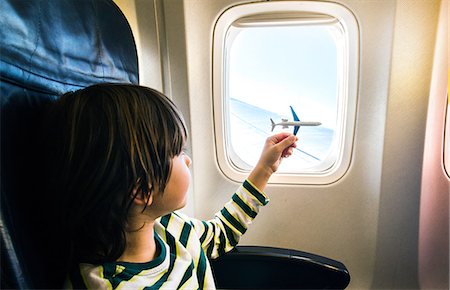 Boy playing with toy airplane at airplane window Foto de stock - Sin royalties Premium, Código: 649-08860218