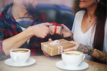 View through window of couple in coffee shop exchanging gifts Stock Photo - Premium Royalty-Free, Code: 649-08860276