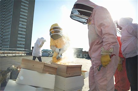 Male and female beekeepers using bee smoker on city rooftop Stock Photo - Premium Royalty-Free, Code: 649-08860445