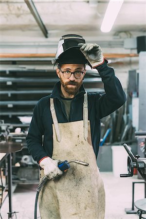 Portrait of metalworker holding welding torch in forge workshop Foto de stock - Sin royalties Premium, Código: 649-08894139