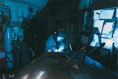 ferro de soldar - Metalworker in welding mask soldering metal in forge workshop Foto de stock - Royalty Free Premium, Número: 649-08894150