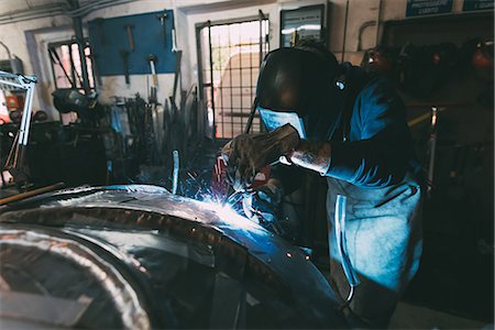 Metalworker in welding mask soldering metal in forge workshop Stock Photo - Premium Royalty-Free, Code: 649-08894152