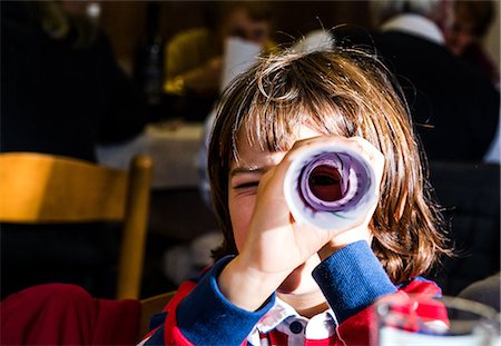 rolled up paper - Portrait of boy looking through rolled paper in cafe Stock Photo - Premium Royalty-Free, Code: 649-08894168