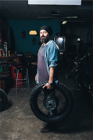 simsearch:649-08894214,k - Portrait of mature man, in garage, holding motorcycle tire Foto de stock - Sin royalties Premium, Código: 649-08894210